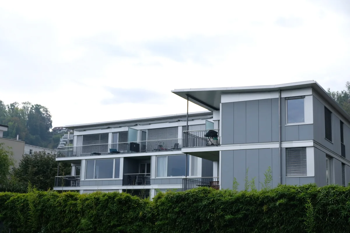 Dreigeschossiges Mehrfamilienhaus aus Glas und mit Flachdach.